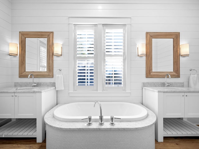 full bath with wood finished floors, two vanities, and a sink