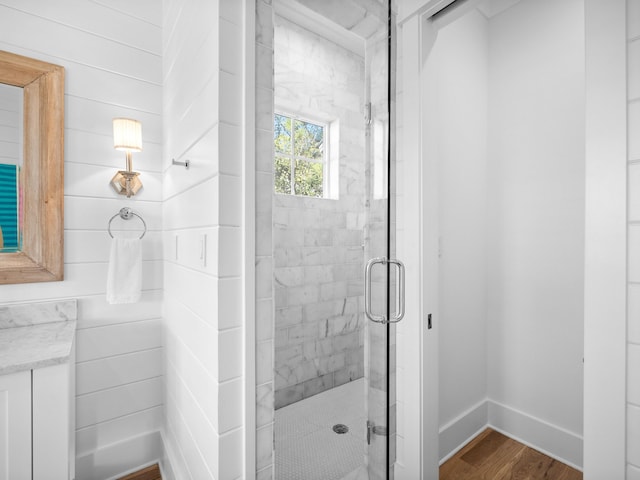 full bathroom with a shower stall, baseboards, and wood finished floors