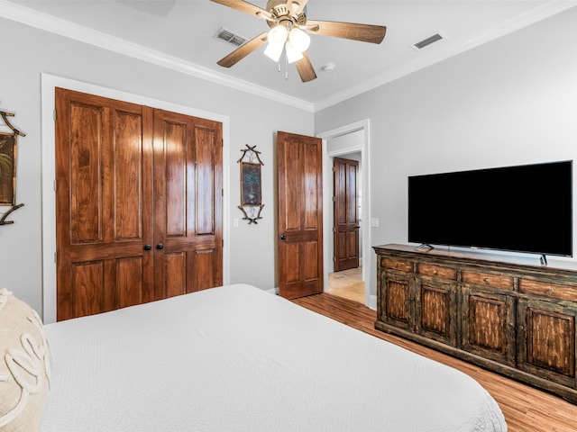 bedroom featuring light wood finished floors, visible vents, and crown molding