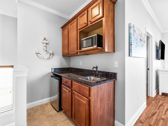 kitchen with baseboards, brown cabinets, stainless steel appliances, crown molding, and a sink