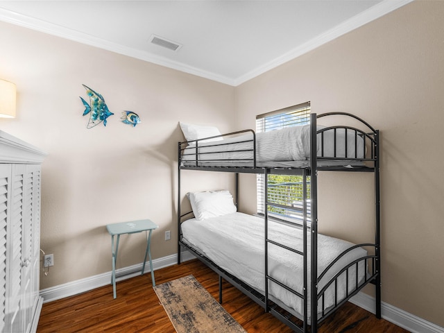 bedroom featuring ornamental molding, wood finished floors, visible vents, and baseboards