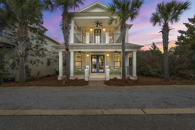 view of front of house with a balcony, ceiling fan, covered porch, a standing seam roof, and french doors