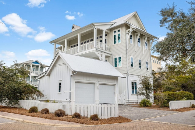 view of front of home featuring driveway, a balcony, a fenced front yard, and board and batten siding