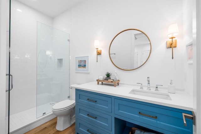 full bathroom with a stall shower, vanity, toilet, and wood finished floors