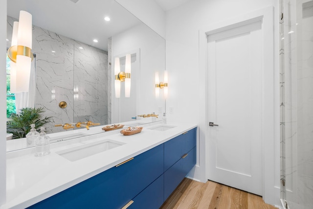 bathroom with recessed lighting, double vanity, a sink, and wood finished floors