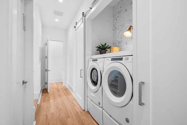 laundry room with washer and clothes dryer, recessed lighting, light wood-style flooring, a barn door, and laundry area