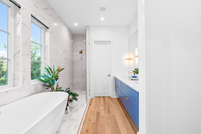 bathroom with plenty of natural light, a freestanding tub, visible vents, and recessed lighting