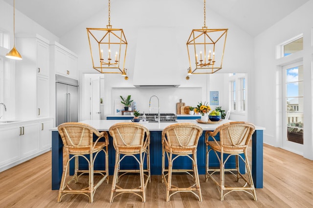 kitchen with a chandelier, a sink, white cabinets, light countertops, and stainless steel built in fridge