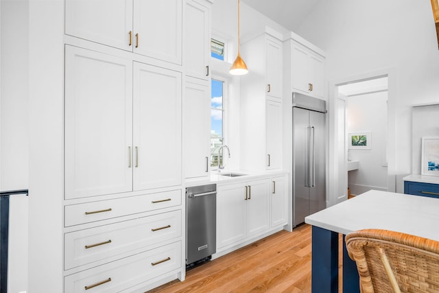 kitchen featuring built in refrigerator, light wood-style flooring, white cabinets, and light countertops