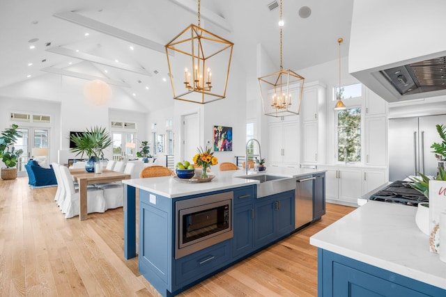 kitchen with built in appliances, blue cabinets, light wood-type flooring, white cabinetry, and a sink