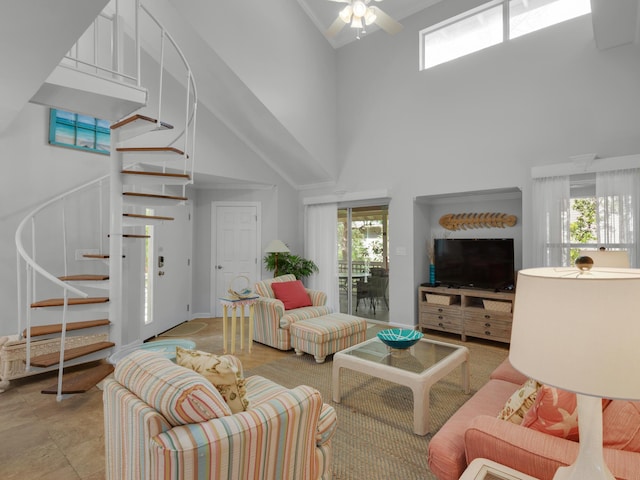 living area with stairs, a towering ceiling, and a ceiling fan