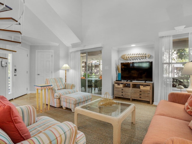 living area featuring vaulted ceiling, ornamental molding, plenty of natural light, and baseboards