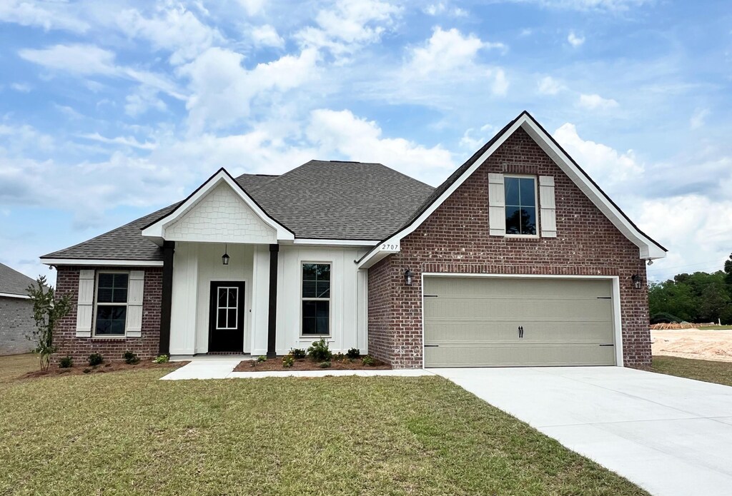 2707 Louis Cir, Crestview, FL 32536 - view of front of house featuring brick siding, concrete driveway, a front lawn, a shingled roof, and board and batten siding