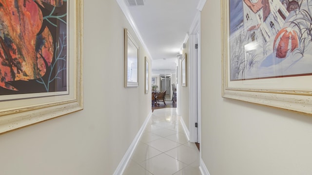 hall featuring light tile patterned floors, visible vents, baseboards, and ornamental molding