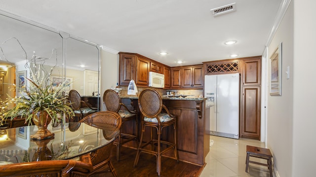 kitchen with visible vents, white appliances, backsplash, and ornamental molding