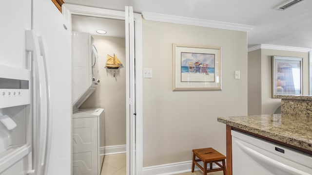 laundry area with visible vents, baseboards, laundry area, stacked washer / drying machine, and crown molding