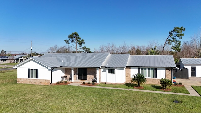 view of front of house featuring metal roof, a front lawn, and brick siding