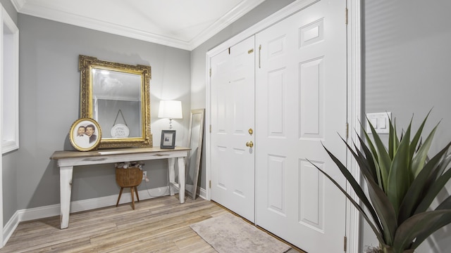 entrance foyer featuring ornamental molding, light wood-style floors, and baseboards