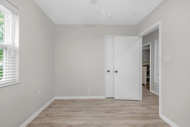 unfurnished bedroom featuring light wood finished floors, multiple windows, a closet, and baseboards