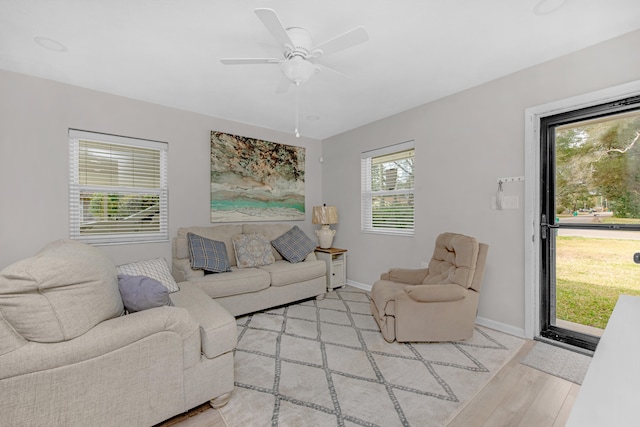 living area with light wood-type flooring, ceiling fan, and baseboards