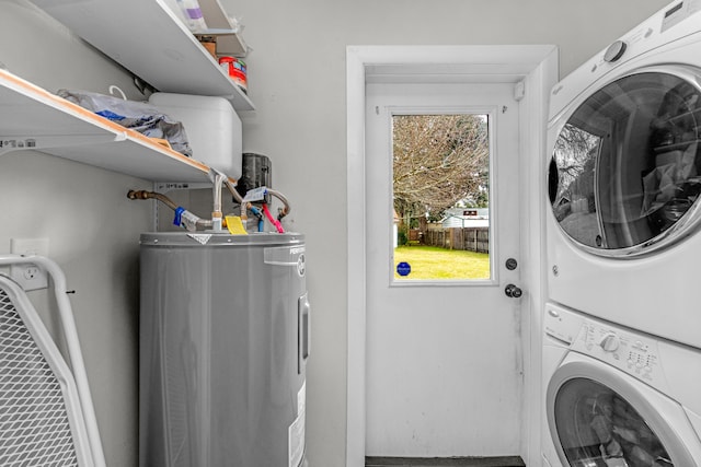 washroom with stacked washer / dryer, laundry area, and electric water heater