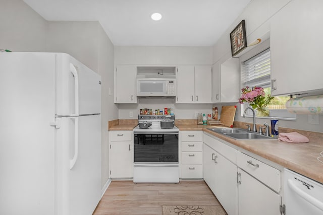 kitchen with light countertops, light wood-style floors, white cabinets, a sink, and white appliances