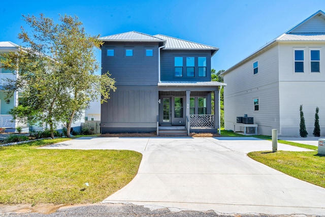 view of front facade featuring a porch, metal roof, a standing seam roof, a front lawn, and board and batten siding