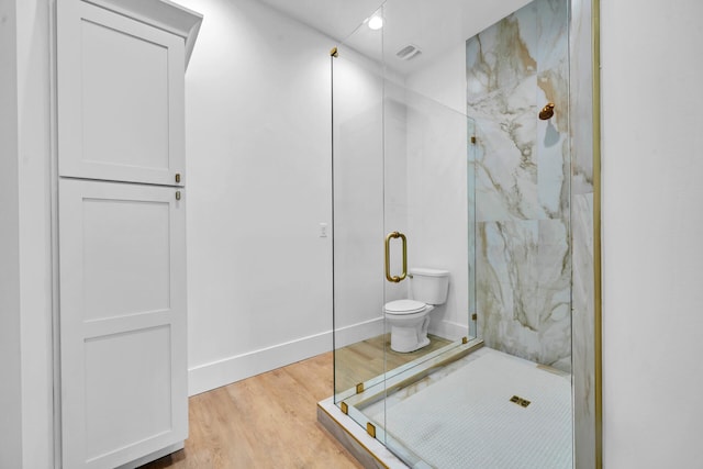 bathroom with visible vents, toilet, a marble finish shower, and wood finished floors