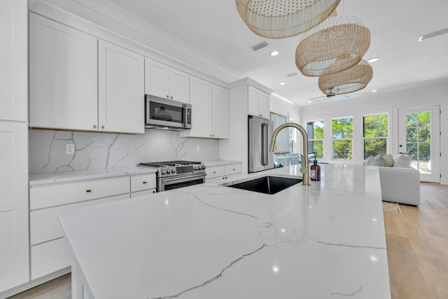 kitchen with a kitchen island with sink, high quality appliances, white cabinetry, and a sink