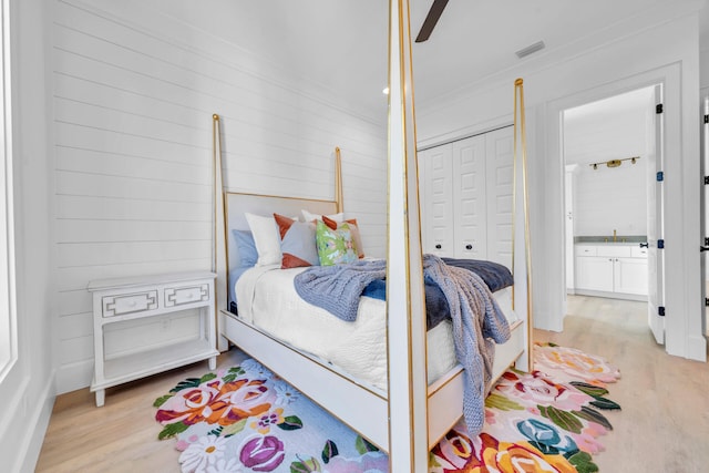 bedroom with light wood-style flooring, visible vents, ceiling fan, and a closet