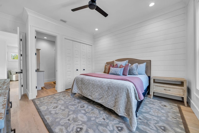 bedroom featuring ornamental molding, a closet, wood finished floors, and visible vents