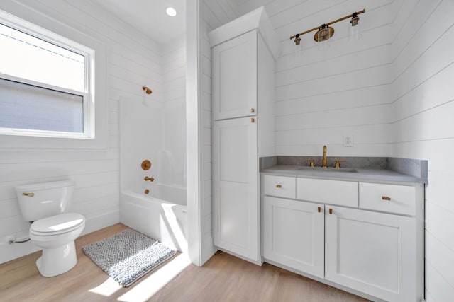 bathroom featuring washtub / shower combination, toilet, wood finished floors, and vanity