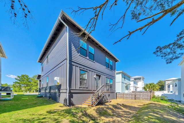 rear view of property featuring fence, a lawn, and board and batten siding