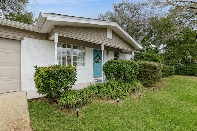 view of front facade featuring a front yard, brick siding, and a garage