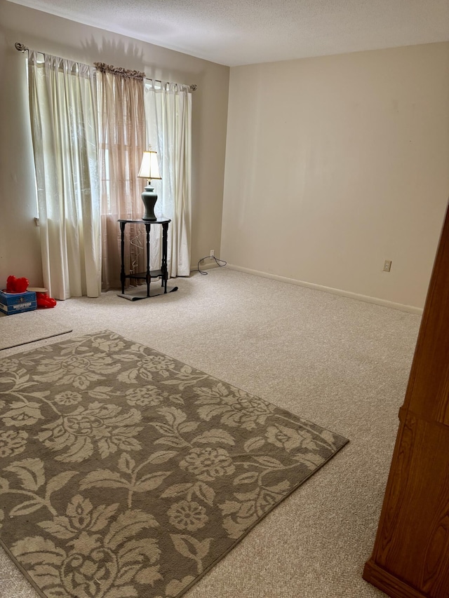 carpeted spare room with baseboards and a textured ceiling