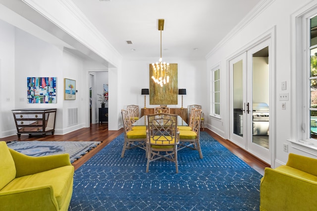 dining room featuring visible vents, crown molding, an inviting chandelier, and wood finished floors