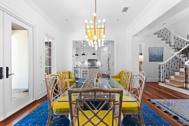 dining area with an inviting chandelier, stairway, wood finished floors, and visible vents