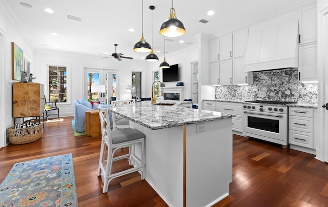 kitchen featuring visible vents, a sink, custom range hood, gas range oven, and open floor plan