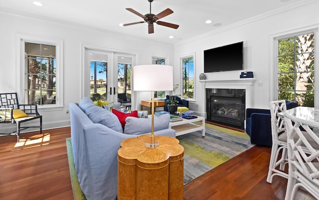 living room with wood finished floors, recessed lighting, french doors, a glass covered fireplace, and crown molding