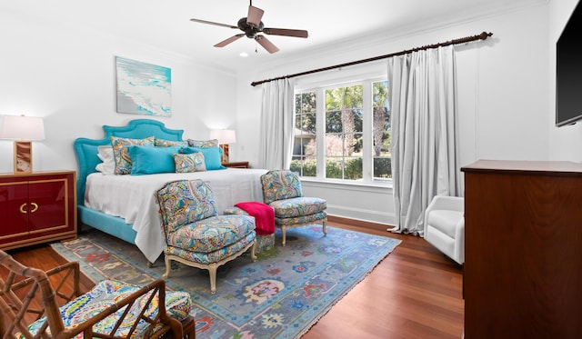 bedroom featuring ceiling fan, crown molding, baseboards, and wood finished floors