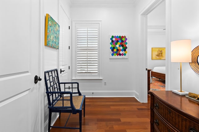 sitting room featuring baseboards, dark wood finished floors, and ornamental molding