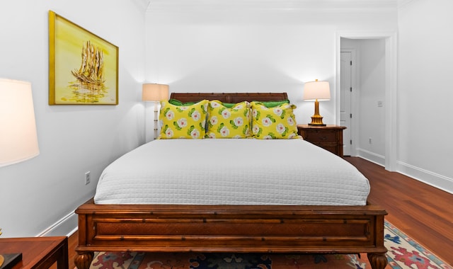 bedroom featuring dark wood finished floors, baseboards, and ornamental molding