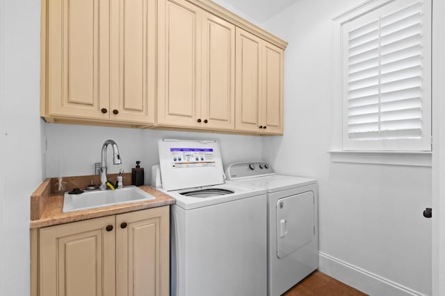 laundry area with cabinet space, independent washer and dryer, baseboards, and a sink