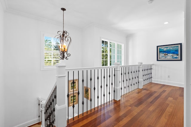 hall featuring an inviting chandelier, crown molding, wood finished floors, and baseboards