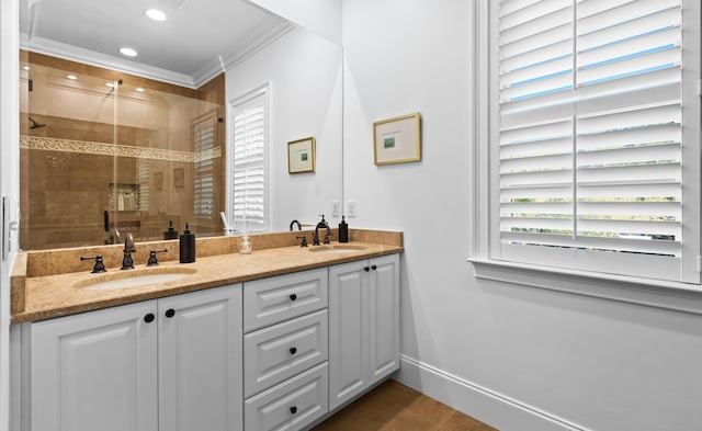 bathroom with a shower stall, double vanity, baseboards, and a sink