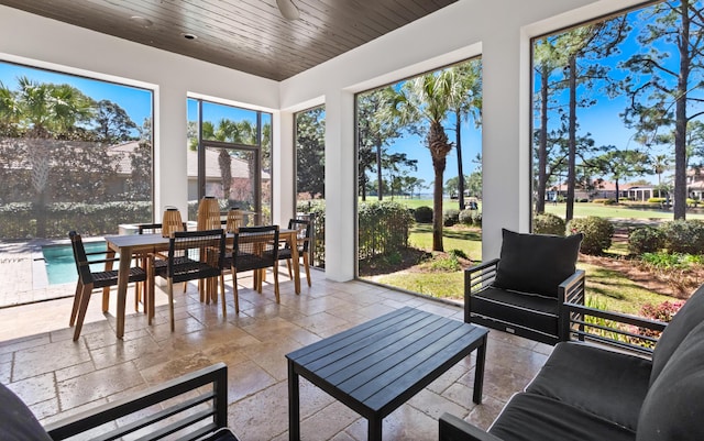 sunroom / solarium with a ceiling fan and wood ceiling