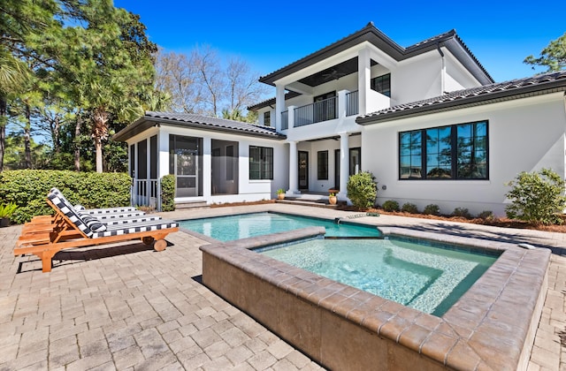 back of house featuring a patio, a balcony, a tile roof, and a sunroom