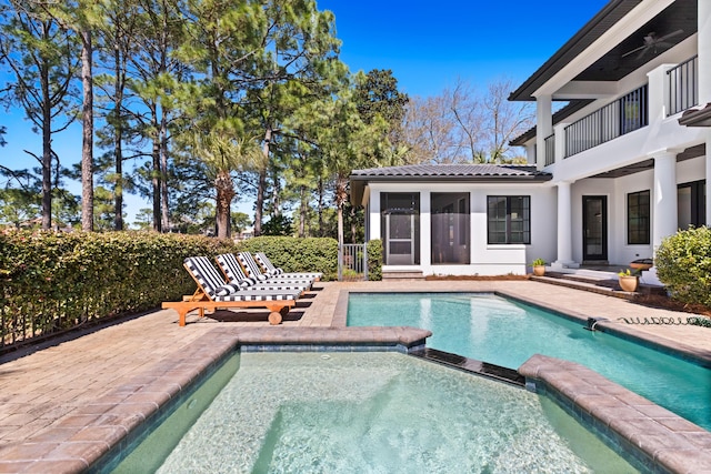 view of swimming pool featuring a pool with connected hot tub, a patio, and a sunroom