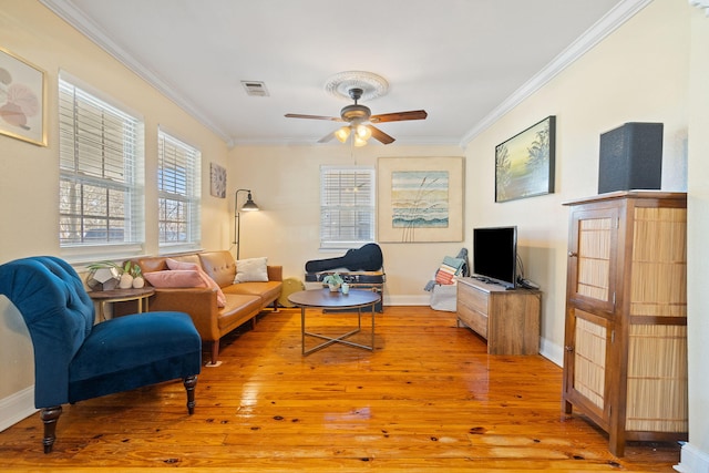 living room featuring light wood finished floors, visible vents, baseboards, a ceiling fan, and ornamental molding