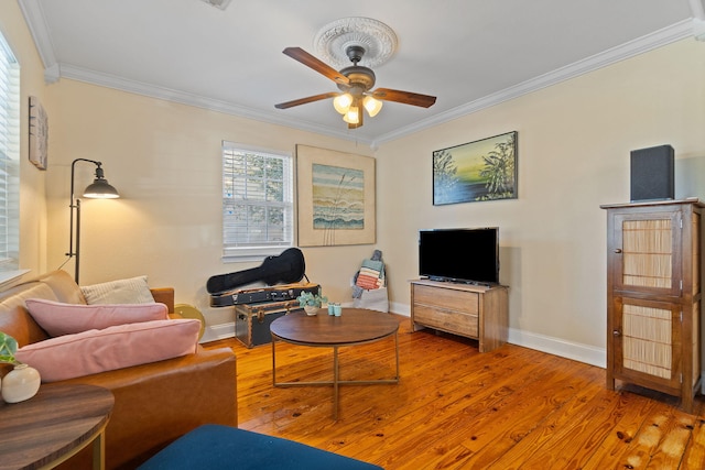 living area with a ceiling fan, crown molding, baseboards, and wood finished floors